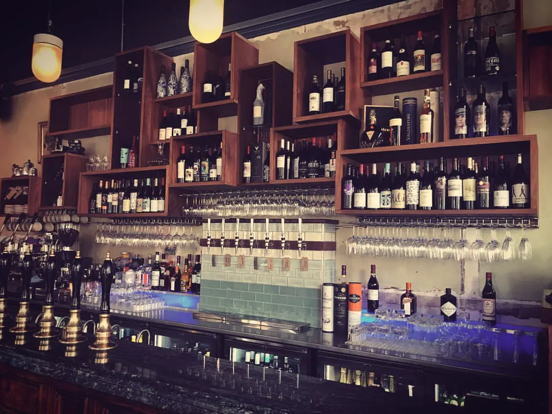 The full back bar at Flok: box shelving of wine and sherry, taps and handpulls