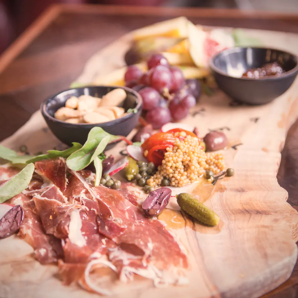 A cheese and charcuterie board on Flok's olive-wood board
