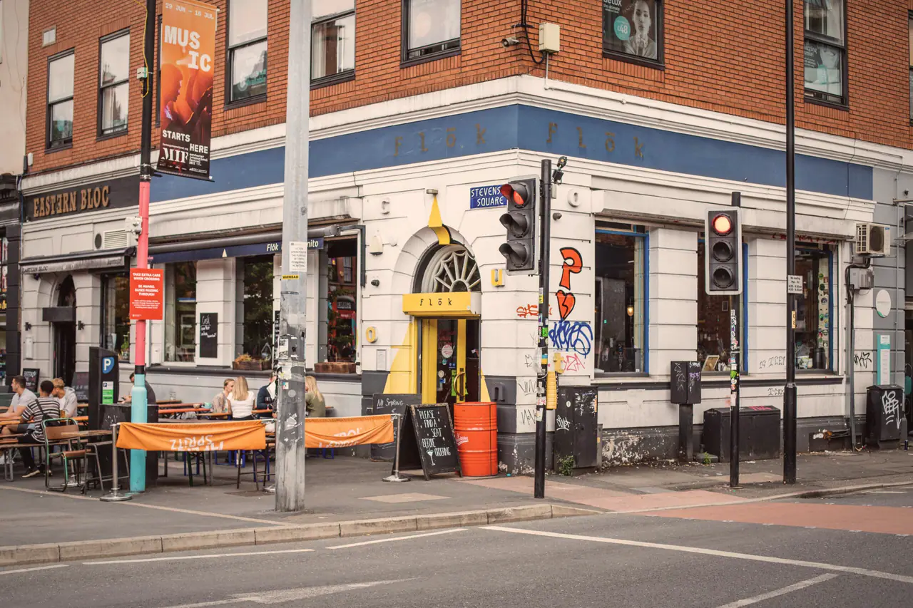 Flok's corner on Stevenson Square, terrace tables busy outside the yellow doorway